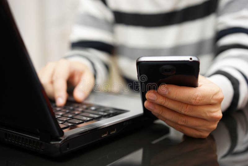 Teenager addicted to the Internet and Social Media using phone and laptop at the same time. Teenager addicted to the Internet and Social Media using phone and laptop at the same time