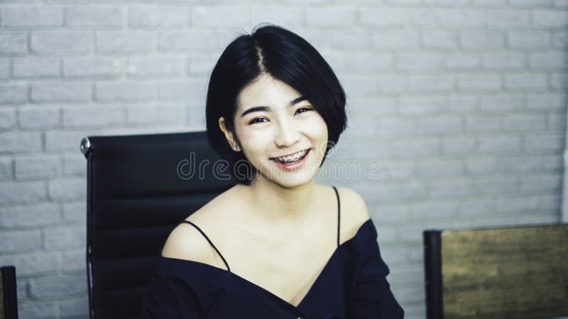Adolescente do retrato do busto no vestido azul luxuoso, sorrindo felizmente com o olhar brilhante, sentando-se na cadeira preta, imagem de stock royalty free Adolescente do retrato do busto no vestido azul luxuoso, sorrindo felizmente com o olhar brilhante, sentando-se na cadeira preta, imagem de stock royalty free