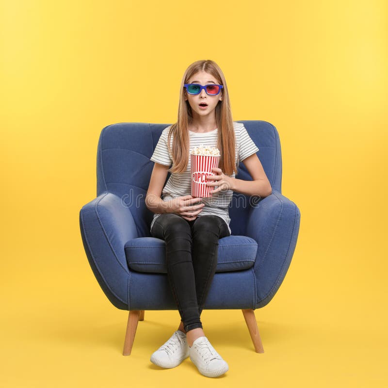 Adolescente emocional com os vidros 3D e a pipoca que sentam-se na poltrona durante a mostra do cinema imagem de stock royalty free Adolescente emocional com os vidros 3D e a pipoca que sentam-se na poltrona durante a mostra do cinema imagem de stock royalty free