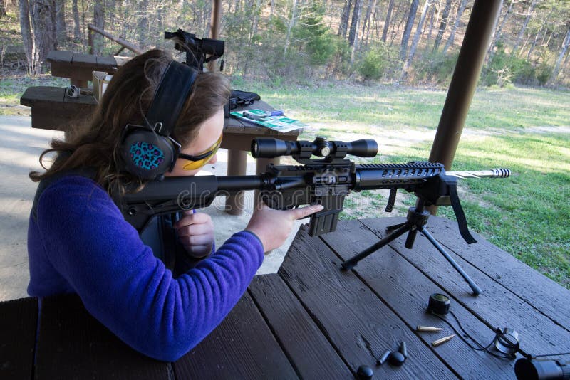 Teenage Girl at shooting range firing an AR-15 rifle. Teenage Girl at shooting range firing an AR-15 rifle.