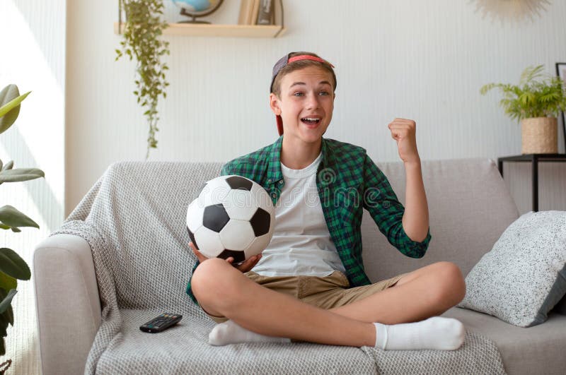 Adolescente entusiasta che guarda la partita di calcio a casa festeggiando la vittoria fotografia stock