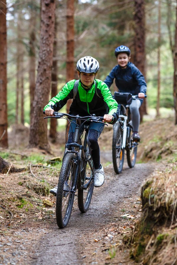 Adolescente et garçon faisant du vélo sur des traînées de forêt photos libres de droits Adolescente et garçon faisant du vélo sur des traînées de forêt photos libres de droits