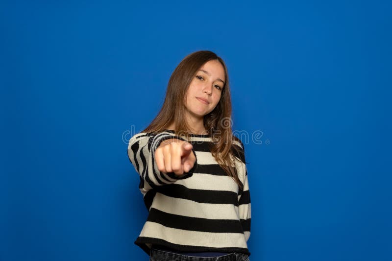 Adolescente ispanico di circa 15 anni con un maglione a strisce che punta la telecamera con una certa soddisfazione fotografia stock