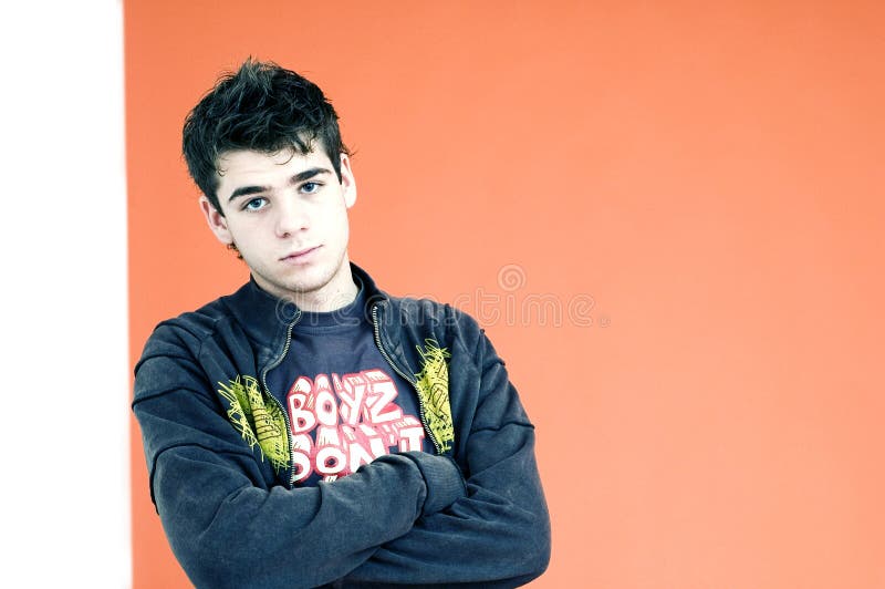 A young teenage boy stands with his arms crossed in a defensive pose in this portrait. A young teenage boy stands with his arms crossed in a defensive pose in this portrait.