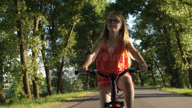 Adolescente louro bonito na viagem da bicicleta no verão