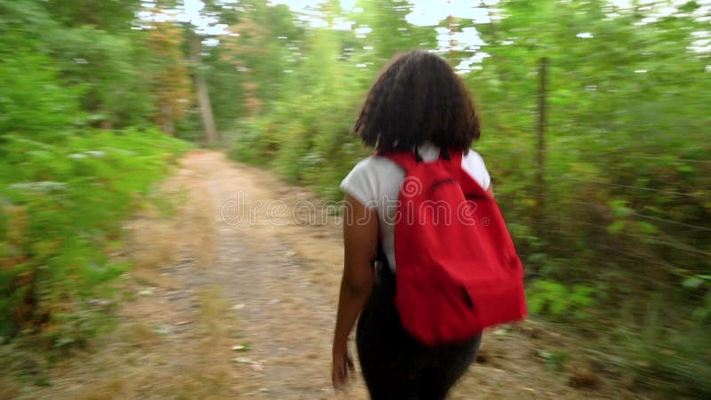 Adolescente métisse race africaine amérique jeune femme randonnée avec un sac à dos rouge et utilisation d'un téléphone portable d clips vidéos