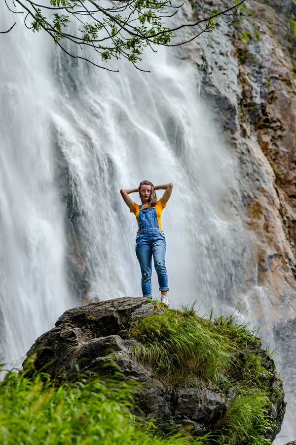 Adolescente novo que está na cachoeira próxima de pedra grande imagens de stock Adolescente novo que está na cachoeira próxima de pedra grande imagens de stock