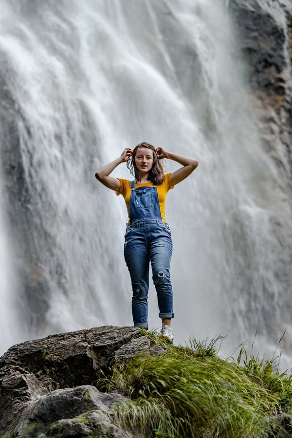Adolescente novo que está na cachoeira próxima de pedra grande foto de stock Adolescente novo que está na cachoeira próxima de pedra grande foto de stock