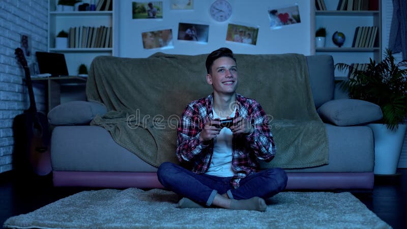 Adolescente que disfruta su ganar en el videojuego, apego del juego, falta de control foto de archivo Adolescente que disfruta su ganar en el videojuego, apego del juego, falta de control foto de archivo