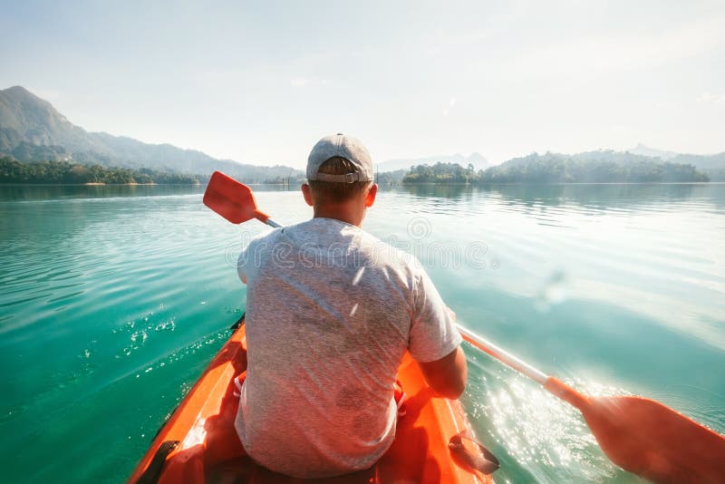 Adolescente que flota en el kajak en el agua tranquila en Cheow Lan Lake, parque nacional de Khao Sok, Tailandia imágenes de archivo libres de regalías Adolescente que flota en el kajak en el agua tranquila en Cheow Lan Lake, parque nacional de Khao Sok, Tailandia imágenes de archivo libres de regalías