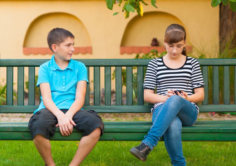 Adolescente que olha com amor na menina indiferente foto de stock Adolescente que olha com amor na menina indiferente foto de stock