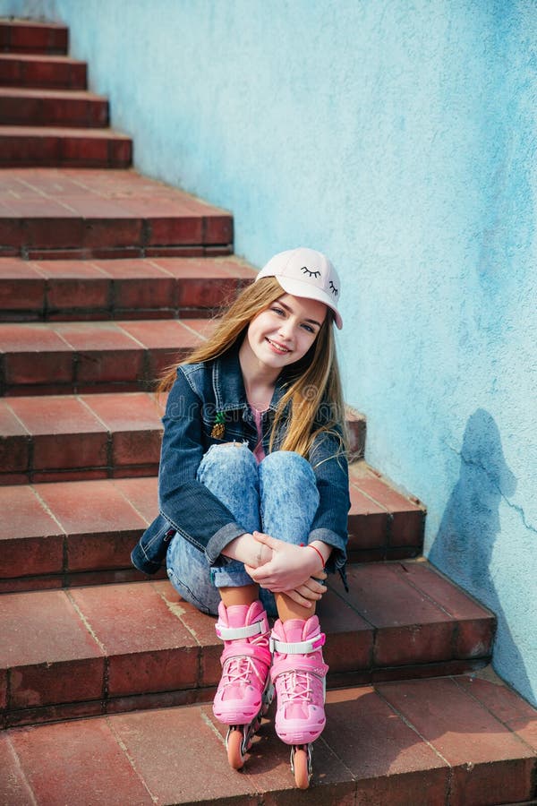 Adolescente que patina na cidade Menina que vai rollerblading o assento na etapa imagem de stock Adolescente que patina na cidade Menina que vai rollerblading o assento na etapa imagem de stock
