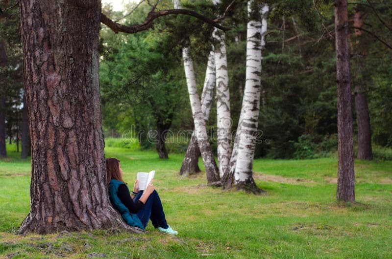Adolescente que se sienta debajo del libro del árbol y de lectura fotografía de archivo libre de regalías Adolescente que se sienta debajo del libro del árbol y de lectura fotografía de archivo libre de regalías