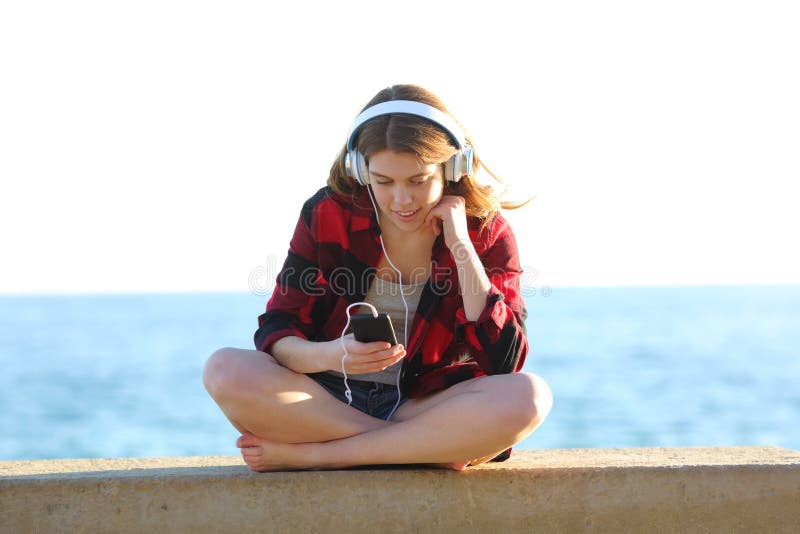 Adolescente relaxado está escutando a música na praia