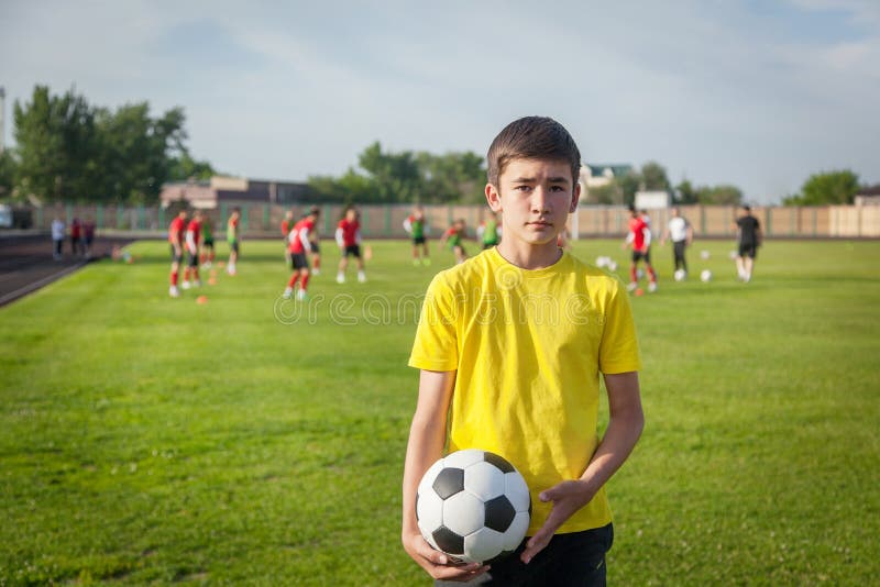 Adolescente serio con un balón de fútbol en su mano contra el b fotos de archivo libres de regalías Adolescente serio con un balón de fútbol en su mano contra el b fotos de archivo libres de regalías
