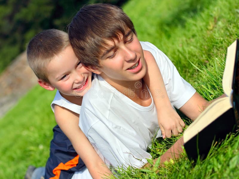 The teenager reads the book to the child. The teenager reads the book to the child