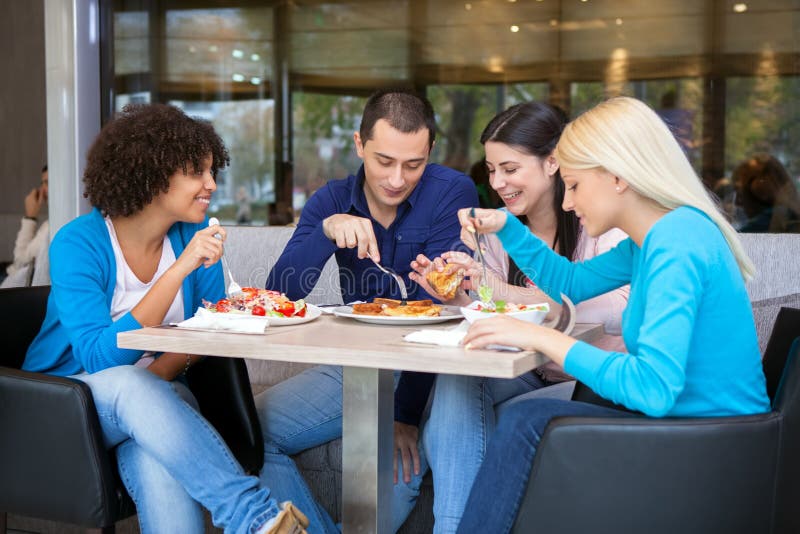 Adolescentes alegres que almuerzan en restaurante imagen de archivo libre de regalías Adolescentes alegres que almuerzan en restaurante imagen de archivo libre de regalías