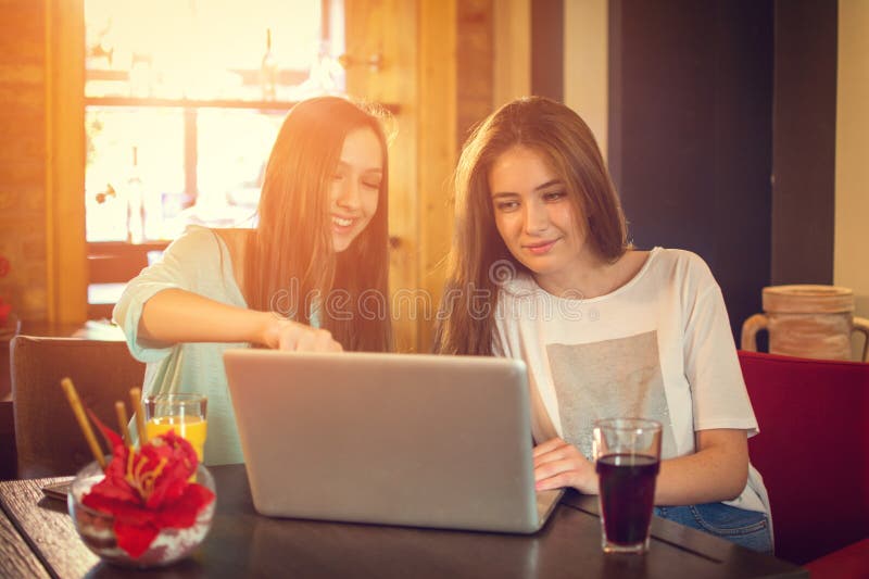 Female teenage friends using laptop in a cafe. Female teenage friends using laptop in a cafe