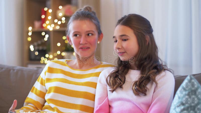 Adolescentes comiendo palomitas de maíz viendo televisión en casa