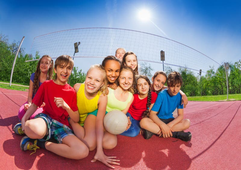 Adolescentes felices que se sientan en corte de voleibol fotos de archivo Adolescentes felices que se sientan en corte de voleibol fotos de archivo
