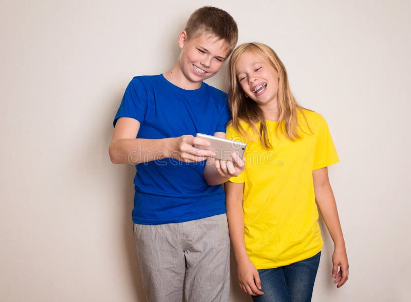 Adolescentes que t?m o divertimento com telefones celulares Estilo de vida e conceito modernos da tecnologia Crian?as que olham a foto de stock Adolescentes que t?m o divertimento com telefones celulares Estilo de vida e conceito modernos da tecnologia Crian?as que olham a foto de stock
