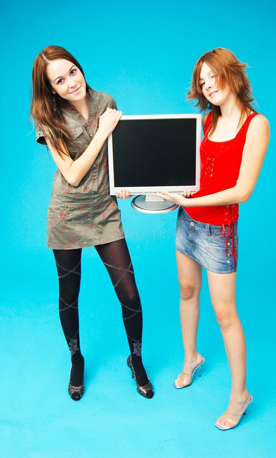 Two teenage girls on each side of a blank computer monitor, holding it between them. Two teenage girls on each side of a blank computer monitor, holding it between them.