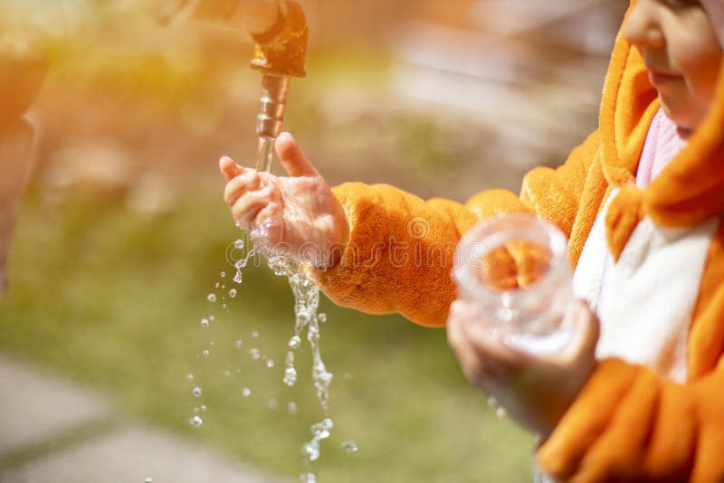 Adorabile bimbo gioca con l'acqua e il rubinetto al sole immagine stock