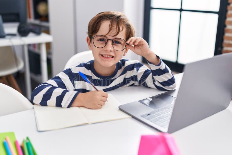Adorabile studente ispanico che scrive su computer su un taccuino in classe fotografia stock