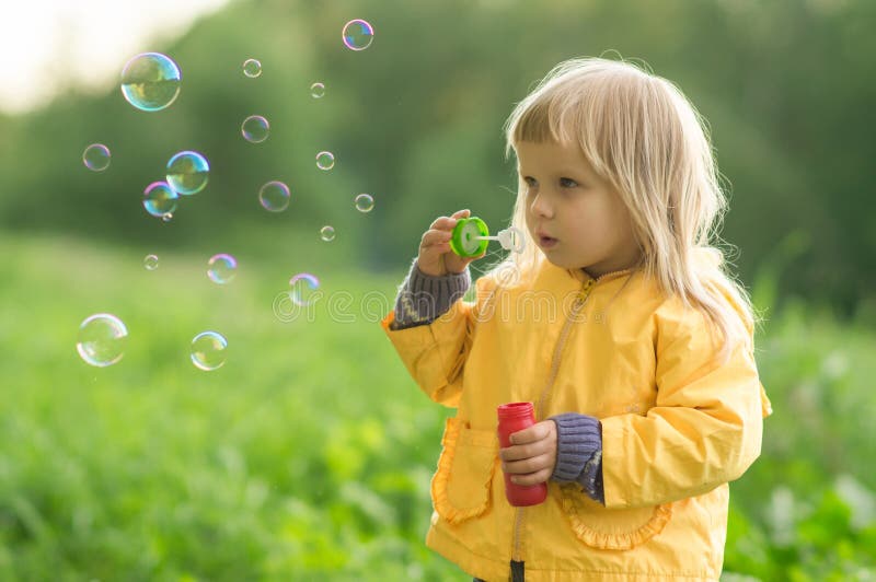 Adorable baby blow soap bubbles in park