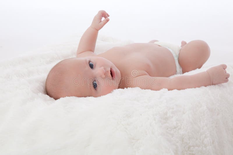 Adorable baby boy lying on fur blanket smiling