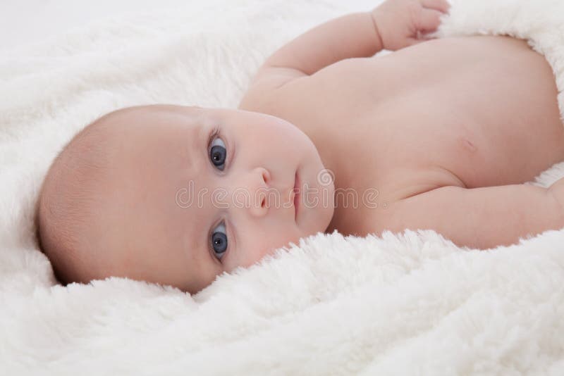 Adorable baby boy lying on fur blanket smiling