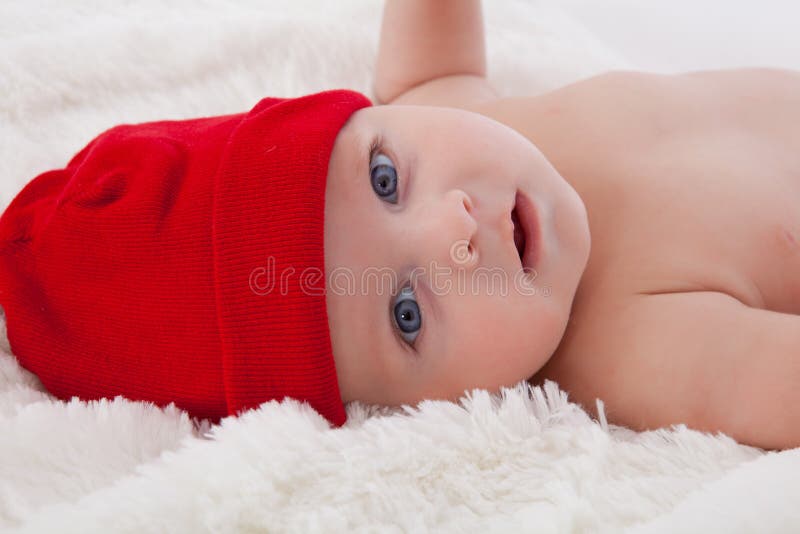 Adorable baby boy lying smiling with red hat on