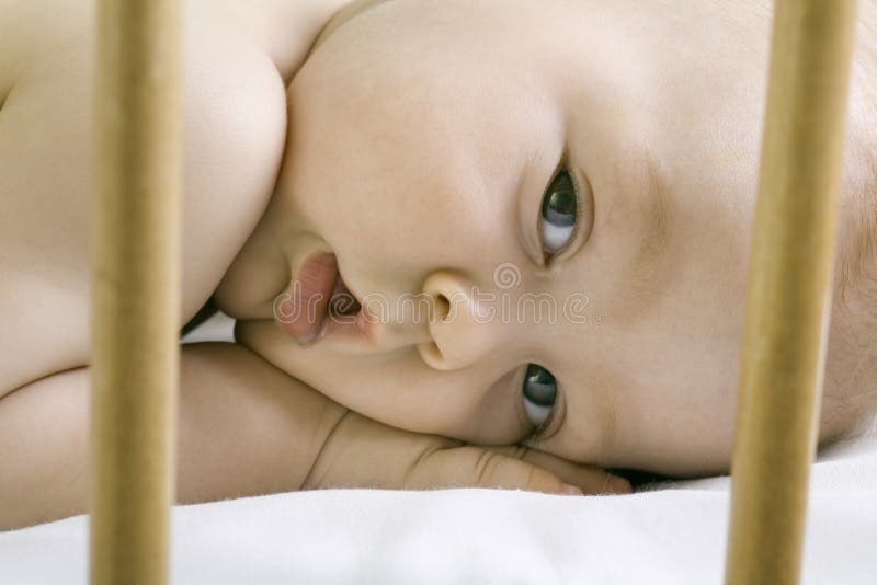 Closeup portrait of adorable baby boy in wooden cot