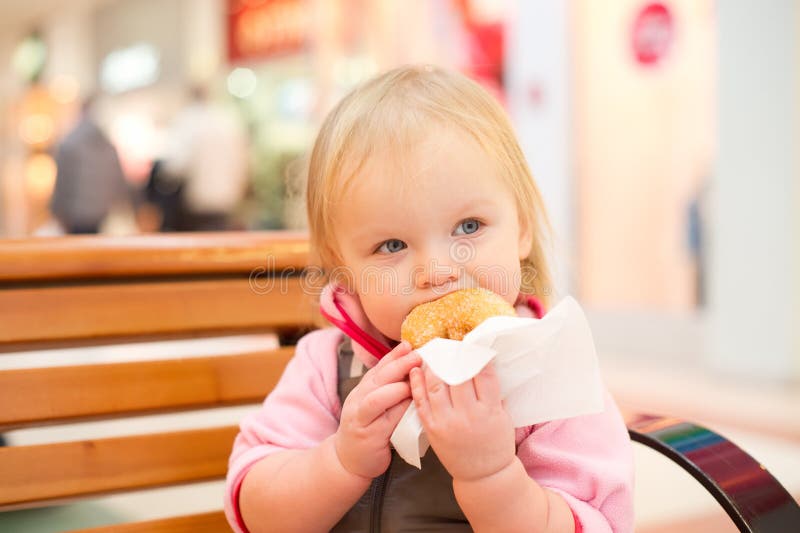 Adorable baby eat donut in mall