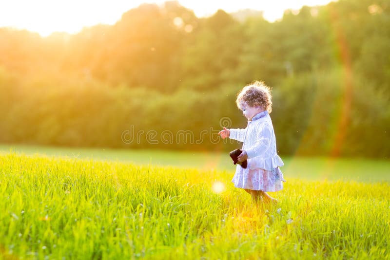 Adorable baby girl in autumn field at sunset