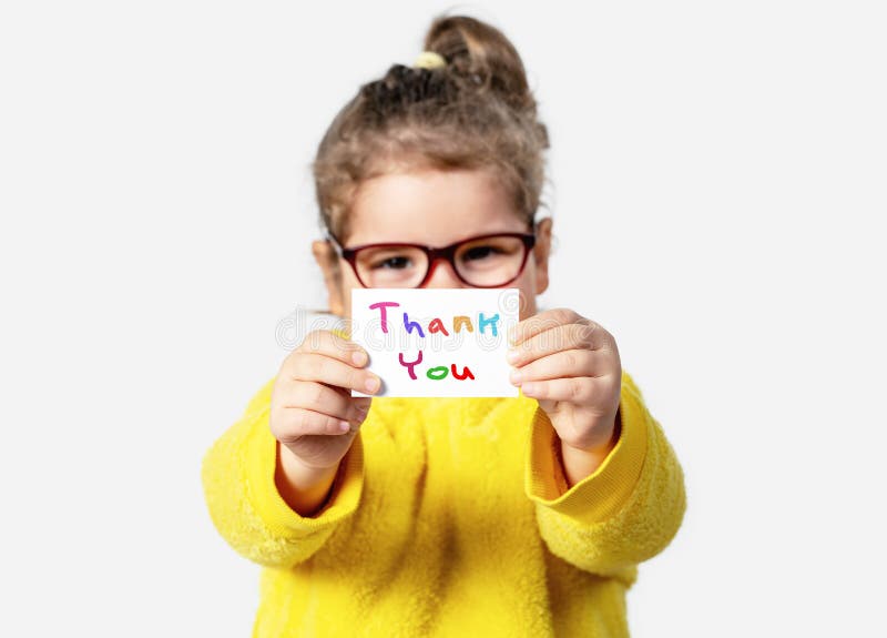 Adorable baby girl is holding a paper with a Thank you note. Silent communication concept. stock photo Adorable baby girl is holding a paper with a Thank you note. Silent communication concept. stock photo
