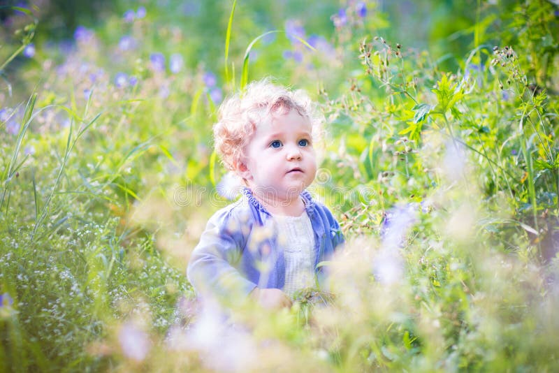 Adorable baby girl playing in garden on sunny summer day