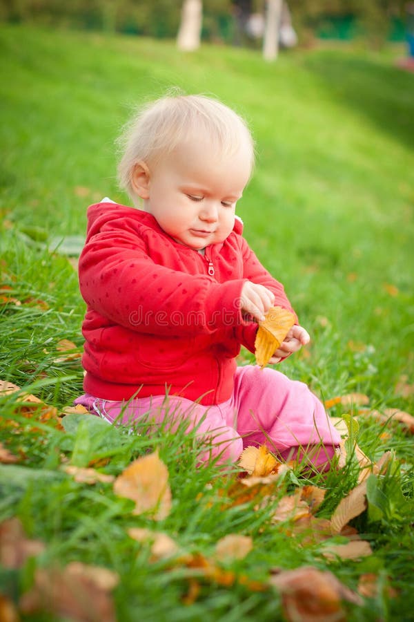 Adorable baby sit on grass play with leaf