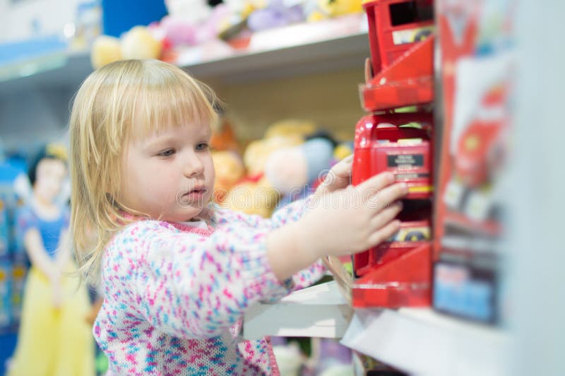 Adorable baby with toys on shelves in mall