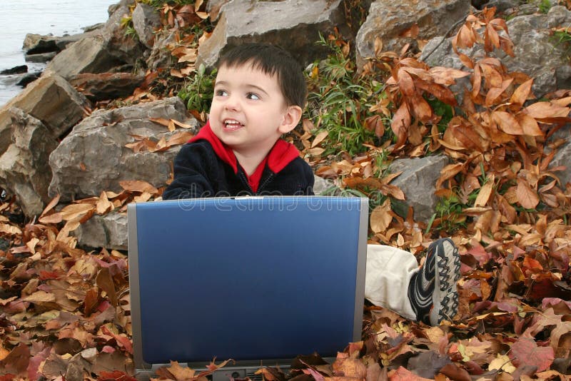 Adorable Boy In Leaves with Laptop