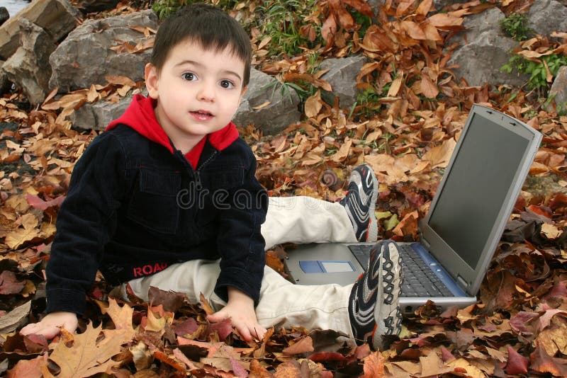 Adorable Boy In Leaves with Laptop