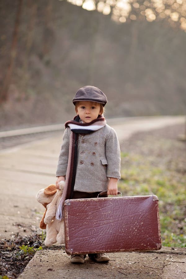 Adorable boy on a railway station, waiting for the train with suitcase and teddy bear royalty free stock photography Adorable boy on a railway station, waiting for the train with suitcase and teddy bear royalty free stock photography