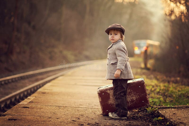 Adorable boy on a railway station, waiting for the train with suitcase and teddy bear royalty free stock image Adorable boy on a railway station, waiting for the train with suitcase and teddy bear royalty free stock image