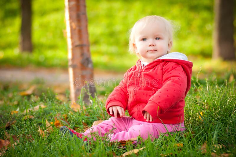 Adorable cheerful baby sit in park on grass stock photo
