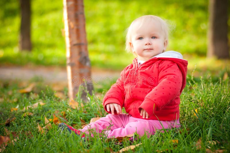 Adorable cheerful baby sit in park on grass