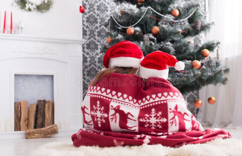 Children in santa hats near christmas tree, wait for holidays