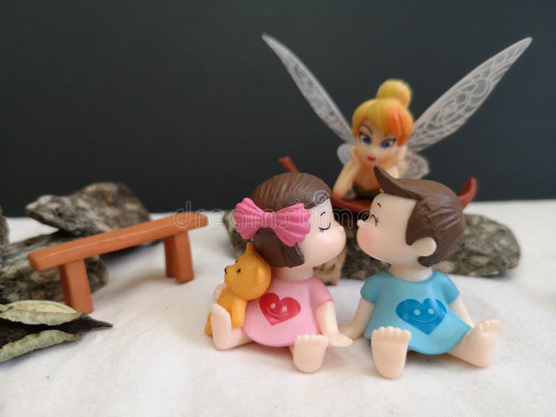 Closeup and macro shot of miniature kissing babies in the garden while fairy Tinkerbell stalking behind.. royalty free stock photo Closeup and macro shot of miniature kissing babies in the garden while fairy Tinkerbell stalking behind.. royalty free stock photo