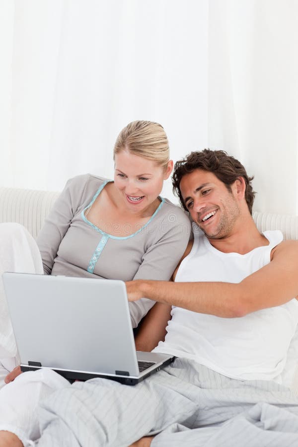 Adorable Couple Looking at Their Laptop on the Bed Stock Photo Image