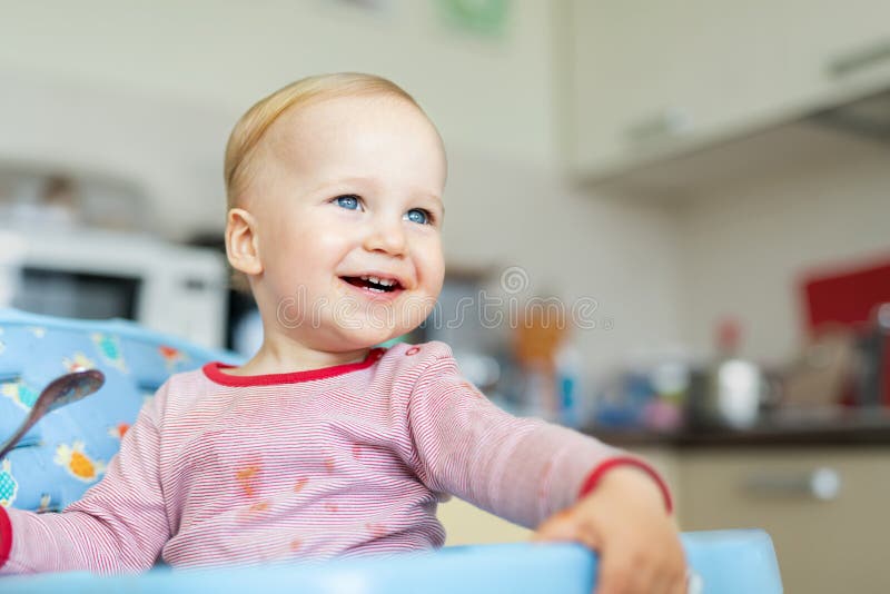 Adorable cute caucasian blond toddler boy eating tasty vegetable soup in chair at kithcen indoor. Mother feeding baby healthy food royalty free stock image Adorable cute caucasian blond toddler boy eating tasty vegetable soup in chair at kithcen indoor. Mother feeding baby healthy food royalty free stock image