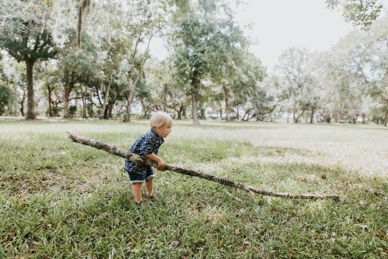 Adorable Cute Precious Little Blond Kleinkind Spielen Outdoor Abenteuer mit Big Stick, Bäume Limb im Hinterhof Wald Naturpark lizenzfreie stockbilder Adorable Cute Precious Little Blond Kleinkind Spielen Outdoor Abenteuer mit Big Stick, Bäume Limb im Hinterhof Wald Naturpark lizenzfreie stockbilder